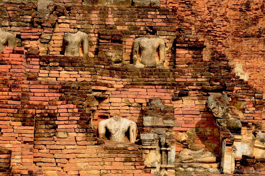 Buddha statues without heads adorn the exterior of Wat Phrapai Luang Temple in Sukhothai, Thailand.