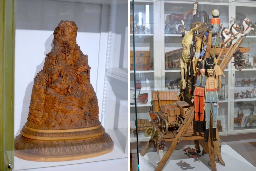 Items on display inside the Oberammergau Museum: on the left, a wooden, handcarved model of the Kofel Mountain. It sits inside a display case. On the right, a wooden 
